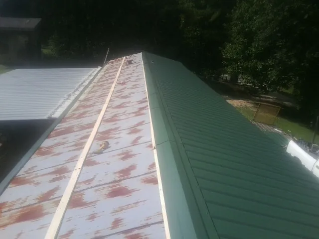 Old rusted panels beside newly installed green metal roofing — Wind Damage Roof Repair by Roofing Brothers in Florissant