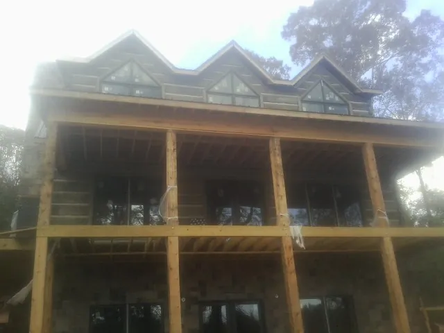 Dormers and porch framing on a large log home under construction — Roof Coating work by our crew in Florissant